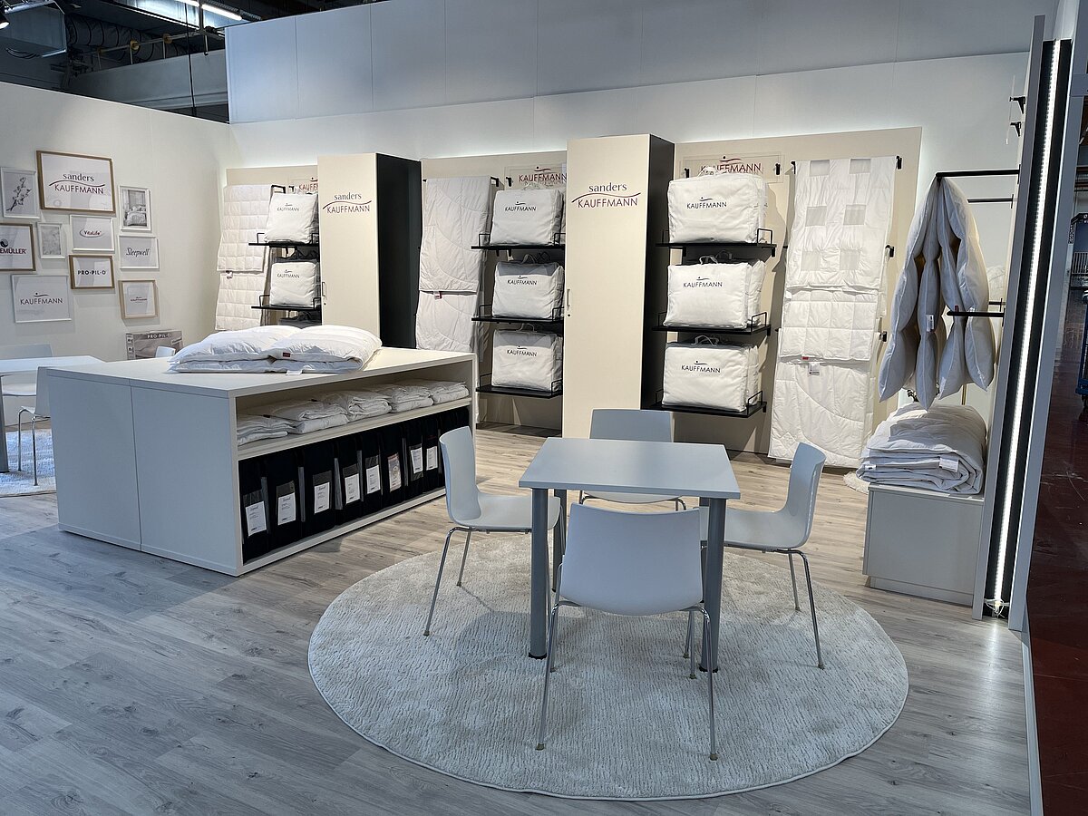 Messestand auf der Hometex 2026 mit beigen Standelementen und präsentierten Bettdecken.