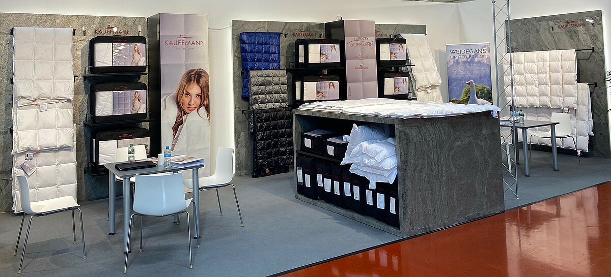 Messestand auf der Hometex 2024 mit ausgestellten Bettdecken und Kissen.