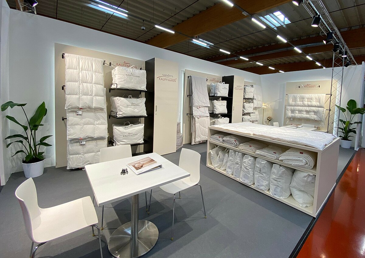 Messestand auf der Hometex 2025 mit ausgestellten Bettdecken und Kissen.