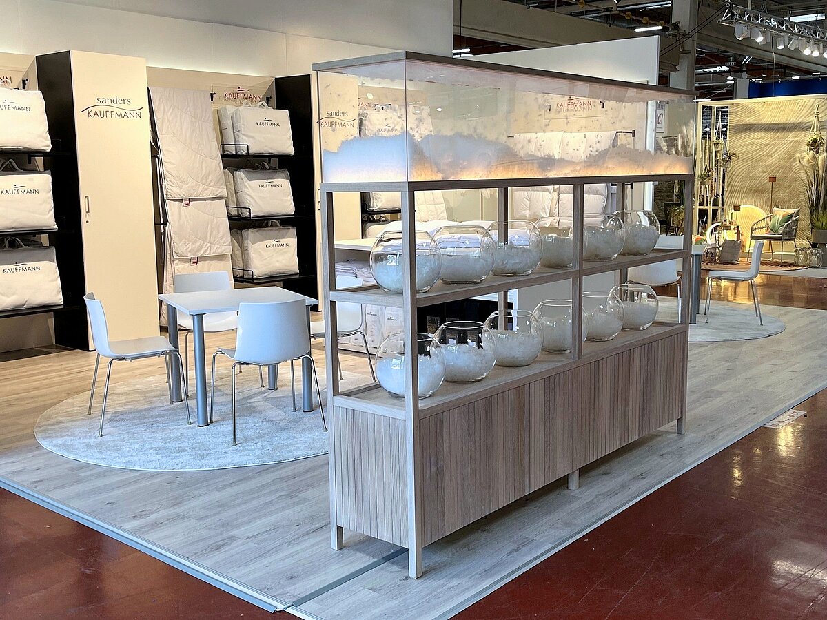 Messestand auf der Hometex 2026 mit beigen Standelementen und präsentierten Bettdecken.