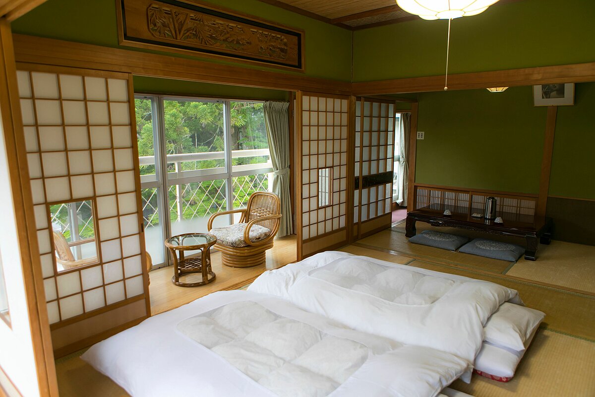 Japanisches Schlafzimmer mit ausgerollten Futons auf dem Boden.