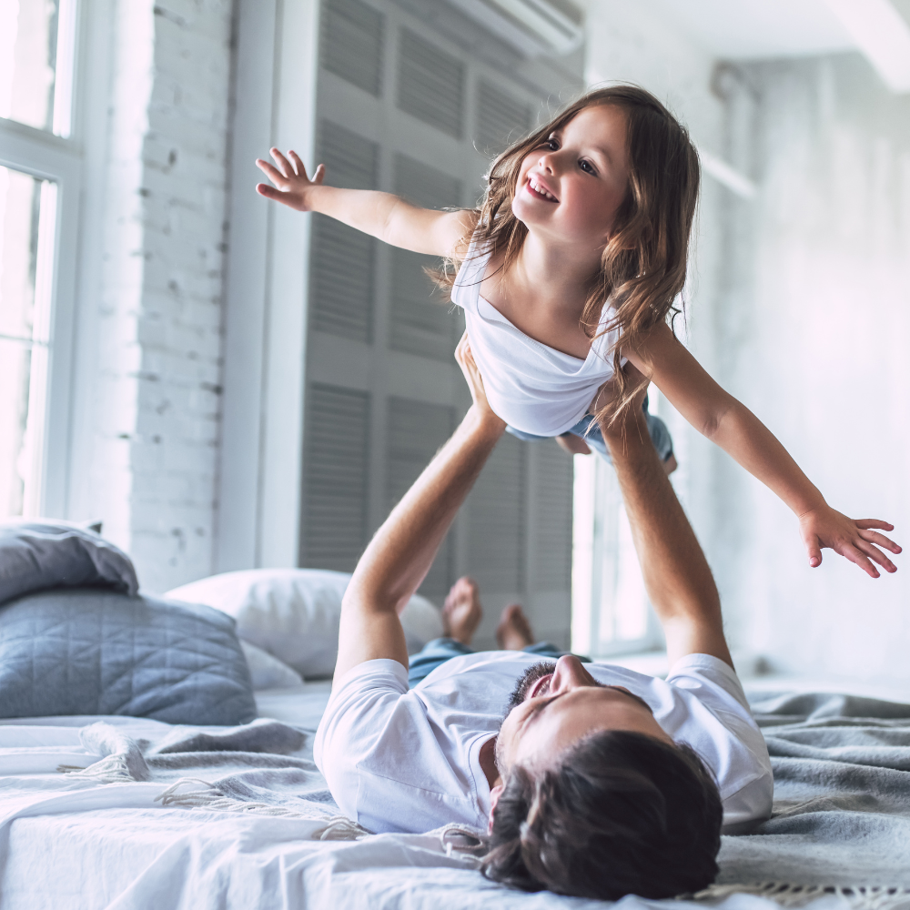 Vater und Tochter liegen im Bett und der Vater hält seine Tochter in den Armen.