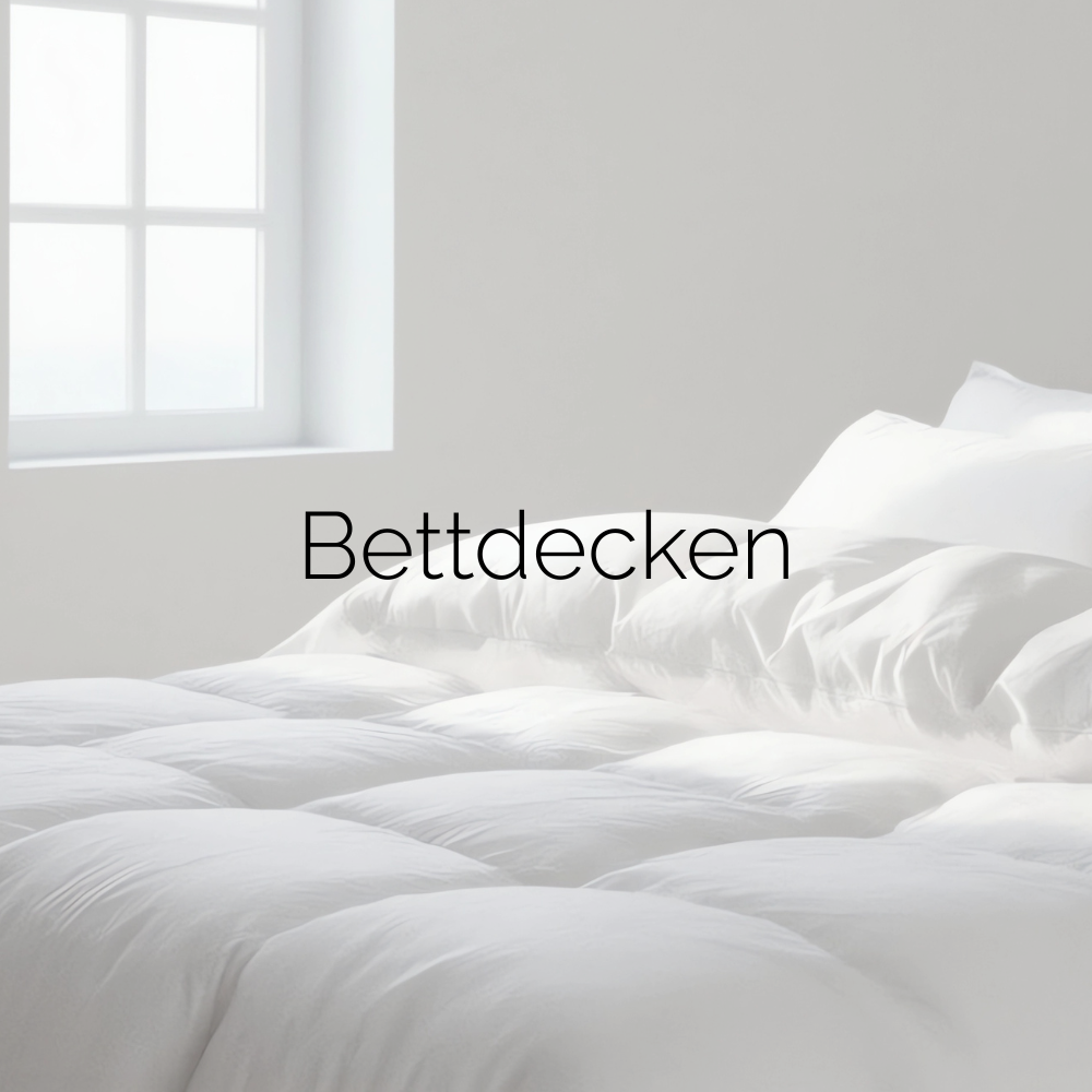 Bett mit weißer Bettdecke und weißen Kopfkissen ohne Bezug. Bildaufschrift "Bettdecken".